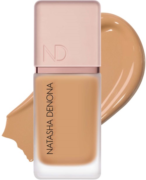 Eine Flasche Foundation mit rosa Deckel und ein Beispeil des beige Make-ups dahinter.