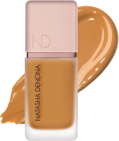 Eine Foundation-Flasche mit rosa Deckel und beige flüssigkeit, mit einer Foundation-Probe dahinter.