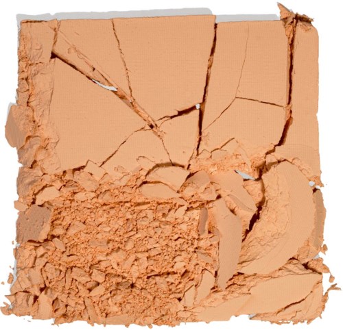 Zerbrochene beige Gesichtspuder mit verstreutem Puder und großen Stückchen.