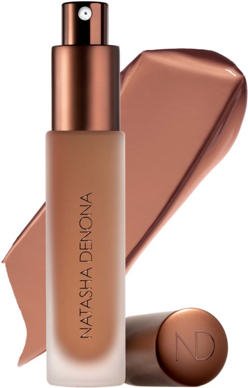 Eine Foundation-Flasche mit metalliclem Deckel und beigefarbener Flüssigkeit, dazu eine Probe und einen Deckel mit Initialen.