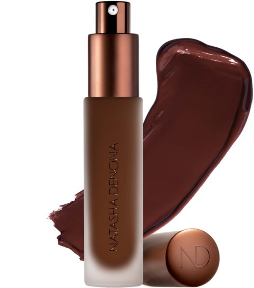 Ein brauner Foundation-Spray mit roségoldener Kappe und passender runder Kompakt, mit einer Make-up-Spur.