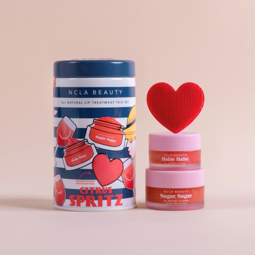 Drie roze lippenbalsemglas met labels, een rode hartversiering en een blauwe container met citrusontwerp.
