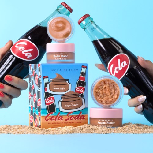 Zwei Hände halten Glasflaschen mit 'Cola'-Aufklebern. Es gibt Gläser mit Balsam und Zucker, im bunten Karton.