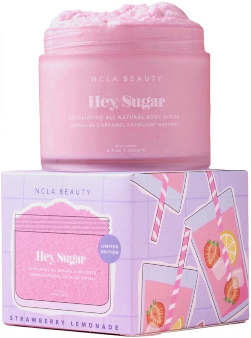 Pink body scrub container on a box with strawberries, lemon, and striped straws, labeled 'Hey Sugar' by NCLA Beauty.