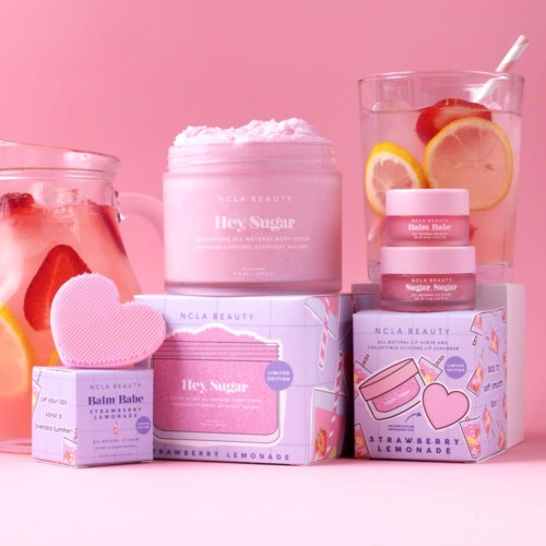 Beauty products and containers are displayed with pink and strawberry-themed packaging, alongside a glass of lemon and strawberry water.