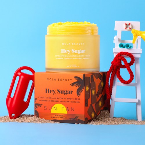 Ein gelber Körperschwamm-Topf, eine orange Schachtel mit "Hey, Sugar" und Sonnenuntergang-Design, ein rotes Sandspielzeug und eine blaue Leiter mit Handtuch.