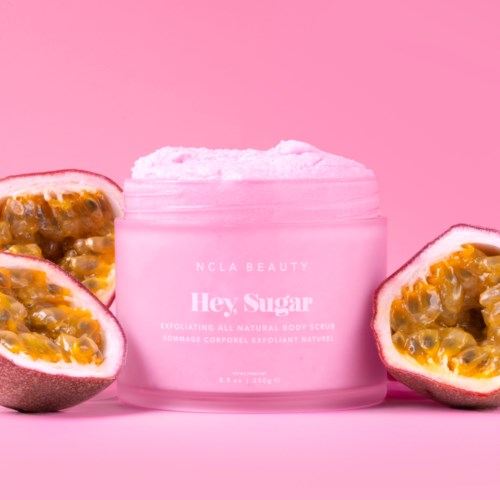 Pink jar labeled 'Hey, Sugar' surrounded by halves of passion fruit on a pink background.