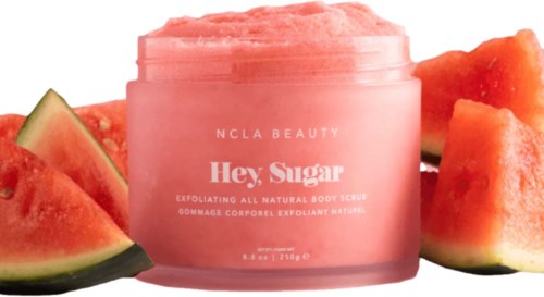Eine rosa Körperpeeling-Behälter mit dem Label "Hey Sugar" und umgeben von Wassermelonenstücken.