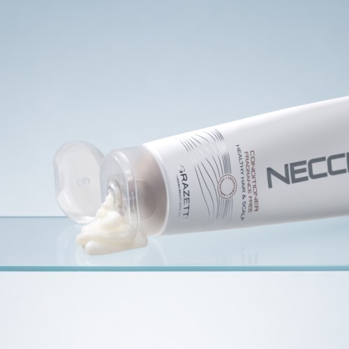 Een tube Neocut Forte crème met wat crème eruit op een glazen oppervlak.