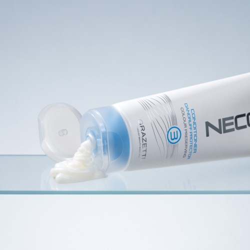 Een witte tube met huidverzorgingscrème met blauwe accenten ligt met deksels eraf, crème stroomt eruit.