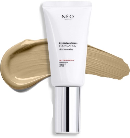 Een witte foundationtube met zilveren dop, met beige make-up streep achter het.