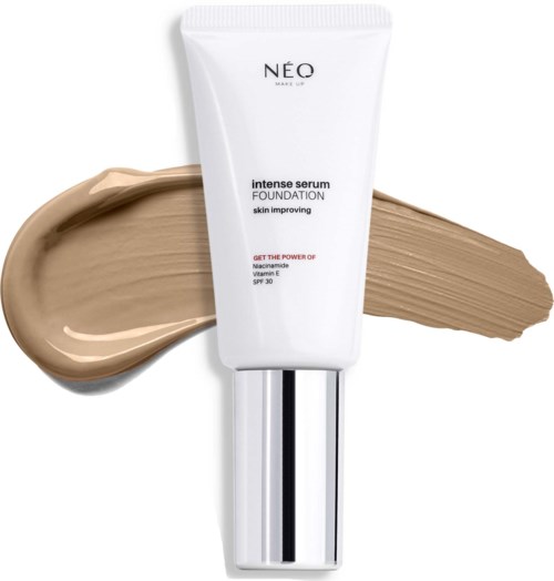 Een witte tube met NEO intense serum foundation staat met beige en bruine vlekken op de achtergrond.