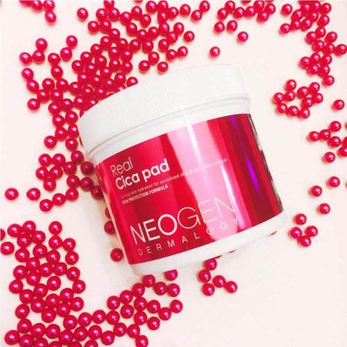 Een roze en witte container met 'NEOGEN' erop, omgeven door kleine roze kralen of balletjes.