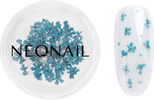 Blue floral-shaped nail decoration next to a white nail with blue flowers on it.