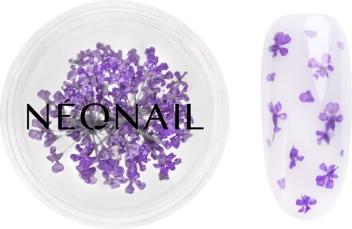 Small purple flower-shaped nail decorations in a clear container and on a nail sample.