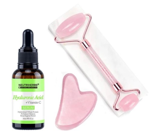 Eine Flasche Hyaluronsäure-Serum, eine rosa Jade-Rolle und ein rosa Gua Sha Werkzeug.