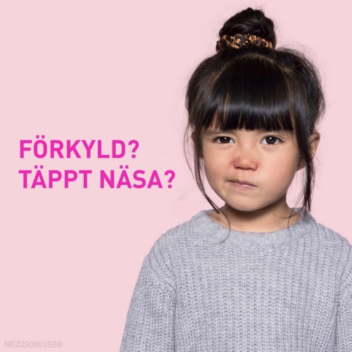 En ung flicka med mörkt hår och hårboll, bär en grå tröja, ser allvarlig ut. Rosa text på svenska frågar om kylig eller täppt näsa.