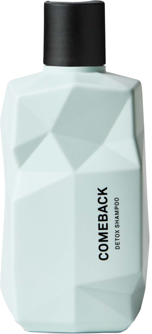Biała butelka z czarną nakrętką oznaczona 'COME BACK DETOX SHAMPOO' z geometrycznym wzorem.