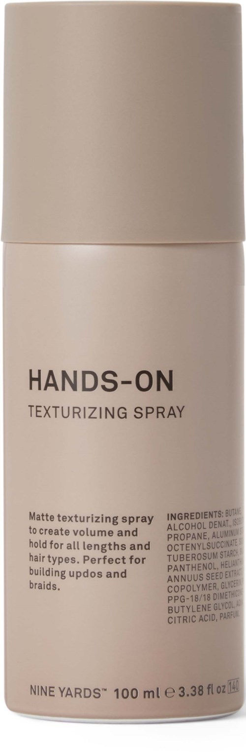 Beżowa butelka spray'u z etykietą 'Hands-On Texturizing Spray' do nadawania objętości i utrwalenia włosów. 100 ml.