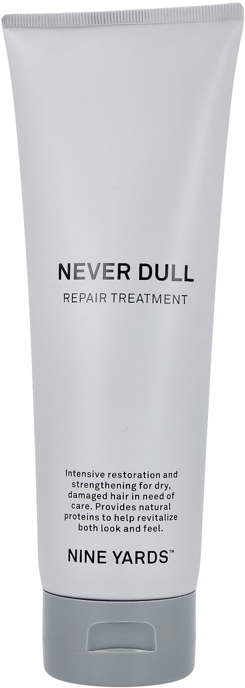 En vit flaska med hårbehandling märkt 'Never Dull Repair Treatment' från Nine Yards, avsedd för skadat hår.