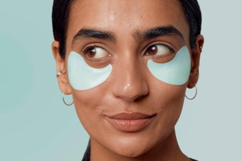 Vrouw met onderooggelpads, licht glimlachend, tegen een lichte achtergrond.