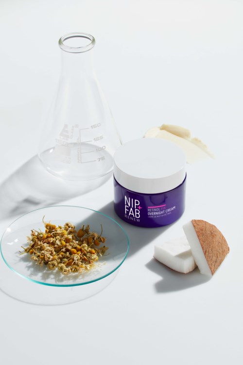 Een huidverzorgingspotje, twee make-up-sponsen, gedroogde kruiden in een schaaltje en een glazen fles op een witte achtergrond.