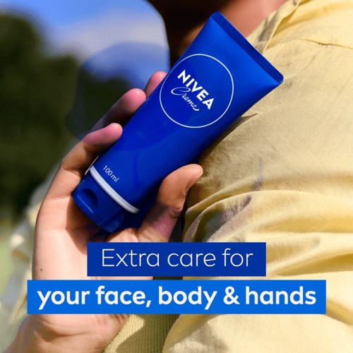 Blauwe tube Nivea-crème met iemand buiten, bevordert huid- en handverzorging.