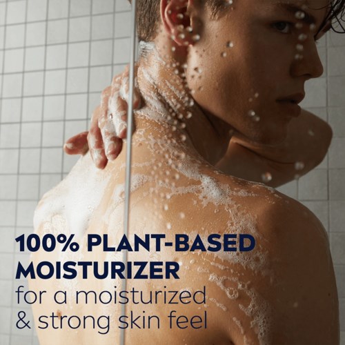 A woman with soap and bubbles on back, looking in the mirror, promoting plant-based moisturizer for skin.