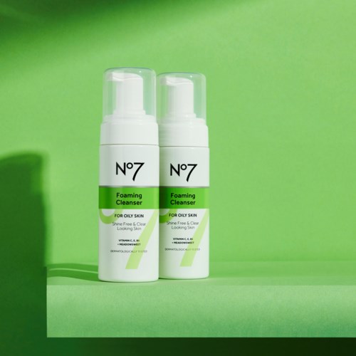 Twee flessen No7 schuimende reiniger met groen en wit label, staan op een groene oppervlakte.