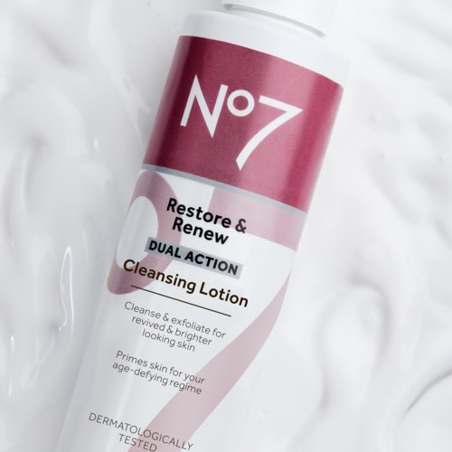 Een witte fles met een roze en witte label die zegt No 7, Restore & Renew DUAL ACTION Reinigingslotion.