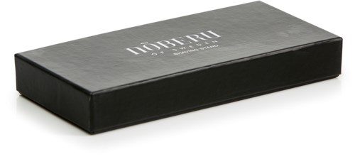 Eine schwarze rechteckige Schachtel mit dem Text "НОВЕЛЛ ЮНЕСКО" auf der Oberseite, möglicherweise eine Produktverpackung oder Schachtel.