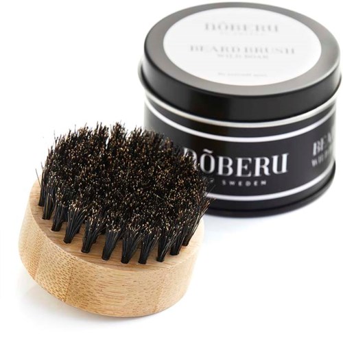 A wooden brush with dark bristles and a round black container with a white label for beard care products.