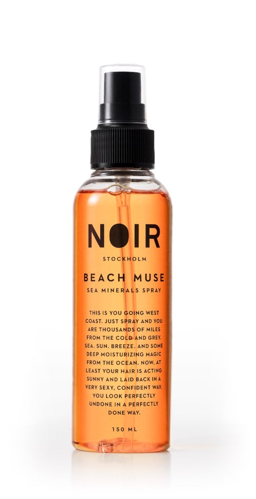 A clear spray bottle with orange liquid, labeled 'NOIR Stockholm Beach Muse Sea Minerals Spray.'