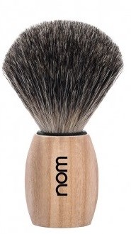 A shaving brush with a wooden handle and black and white bristles, labeled 'nom'.