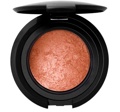 A round makeup compact with orange blush inside, black case, and a lid partially open.