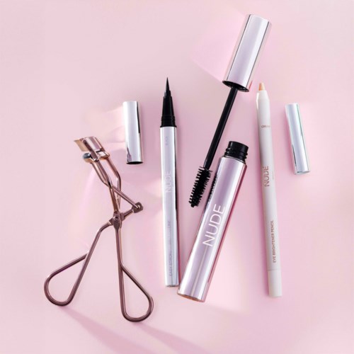 A collection of makeup tools including an eyeliner pen, mascara, eyelash curler, and lip products on a pink background.