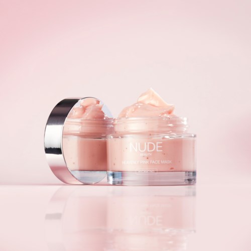 Ein Glas mit rosa Gesichtscreme und silbernem Deckel auf hellem rosa Hintergrund.