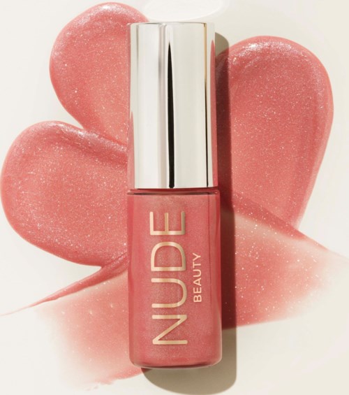 A coral pink nail polish bottle with a shiny silver cap, placed on a pink glittery background.