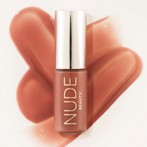 A bottle of nude-colored lipstick with a silver cap stands in front of swatched lipstick shades.