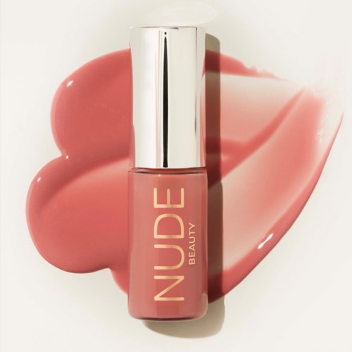 Nude pink nail polish from Nude Beauty with a silver cap, on a pink cosmetic smear.