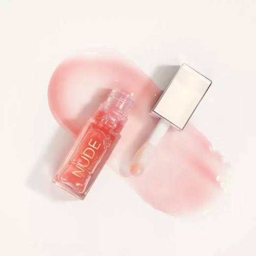 A bottle of nude-colored nail polish with a swatch and some pink cream spots.