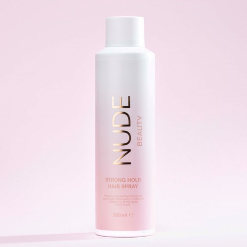 En hvit flaske med rosa og gull tekst for NUDGE Beauty's strong hold hårspray mot en lys rosa bakgrunn.