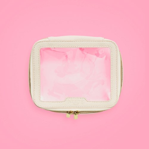 A small, light-colored bag with a clear plastic front and a gold zipper, placed on a pink background.