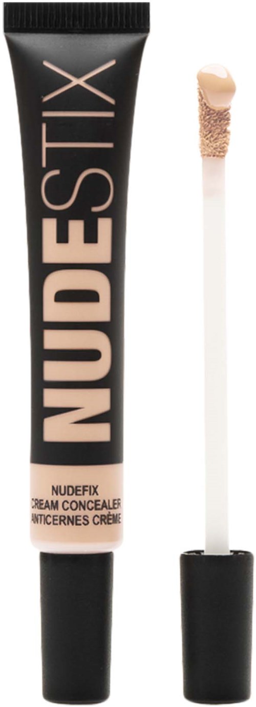 A black tube of concealer with the word NUDESTIX, and a white applicator stick with a beige tip.
