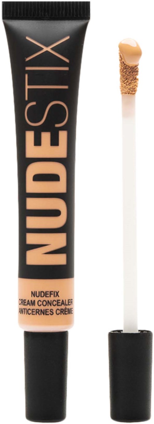 Een tube NUDESIX concealer met bijbehorende applicatorborstel ernaast, gemerkt "NUDECIX," in zwart en perzikkleuren.