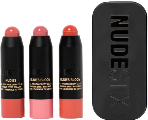 Drie lippenbalsems in roze en koraal, met zwarte vulpenhoezen en een zwart opbergetui met de merknaam NudeStix.