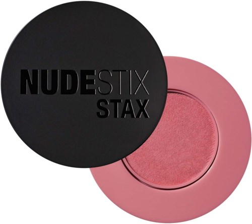 Een zwarte ronde make-updoos met de tekst "NUDESTIX STAX" en een roze ronde blush of oogschaduw.