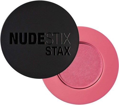Een zwarte ronde container met de woorden "NUDESTIX STAX" erop, gedeeltelijk over een roze ronde container.