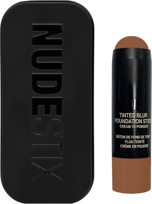 Een zwarte rechthoekige verpakking met 'NUDESTIX' erop en een tube getinte wenkbrauw foundation stick daarnaast.