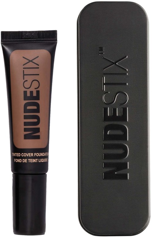 Eine Tube mit Nude-Foundation und eine schwarze rechteckige Box mit dem Markennamen 'NUDESTIX' geprägt.